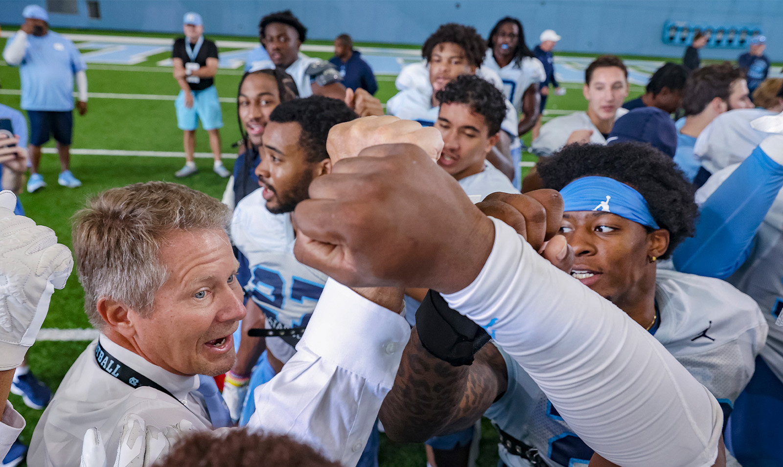 Chancellor Kevin M. Guskiewicz leading a huddle and chant with Carolina football players at one of their practices.
