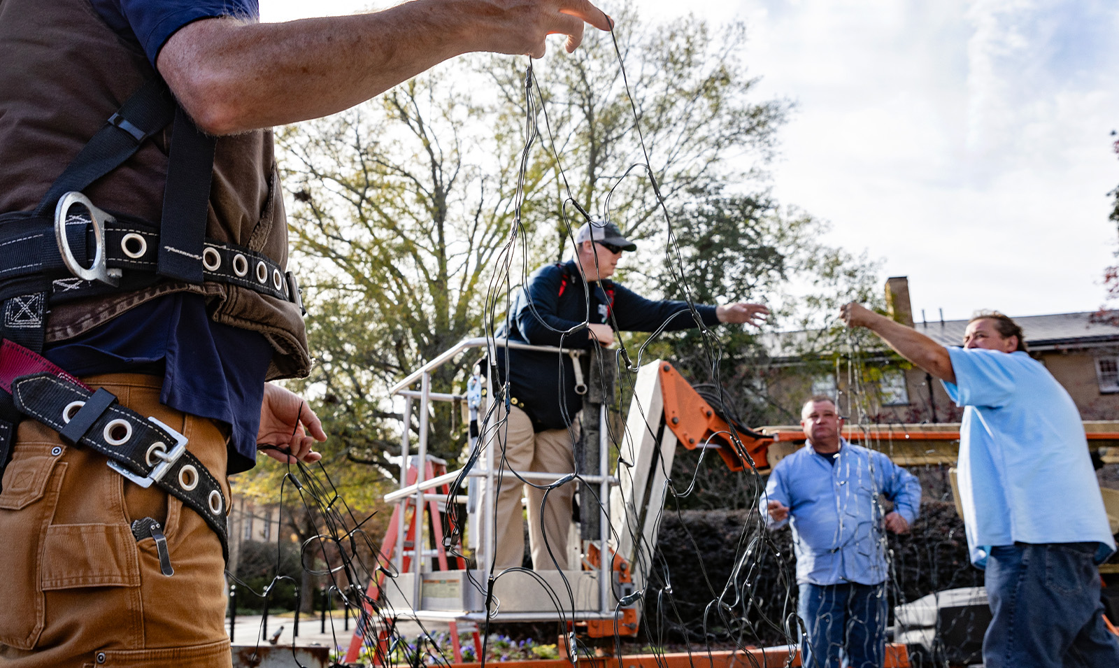 Workers holding a string of hoilday lights as they prepare to place them on the Old Well on the campus of UNC-Chapel Hill.
