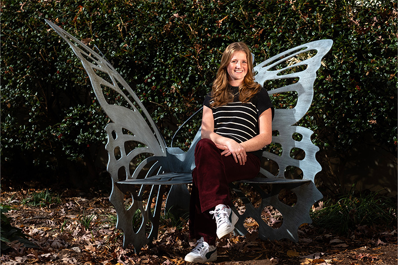 A UNC-Chapel Hill student and executive director of the student-run Eve Carson Scholarship, Emily Smither, poses for a portrait while sitting on the Carolina Blue butterfly bench on campus. The bench is dedicated to former student body president Eve Carson, who was murdered in 2008.