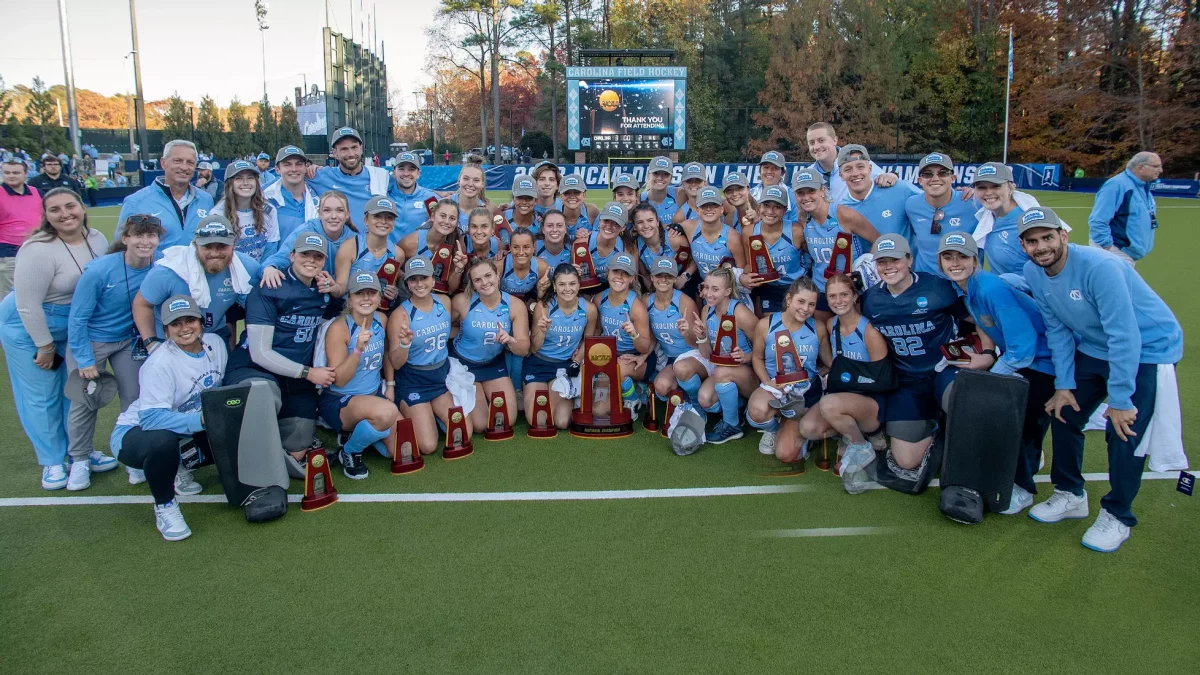 The Carolina field hockey team posing for a team photo with the NCAA championship trophy on the field at Karen Shelton Stadium on the campus of UNC-Chapel Hill
