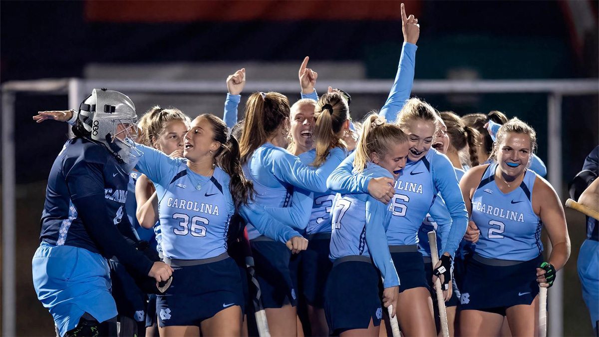 Members of the Carolina field hockey team embracing and celebrating a conference championship victory.
