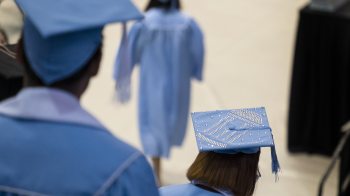 Graduates in caps and gowns walking down steps.