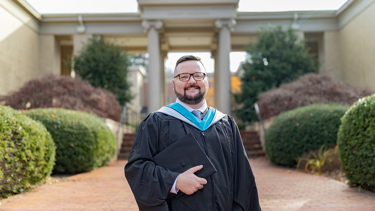 Hogan Medlin poses for a portrait outside of the School of Government wearing ceremonial robes.