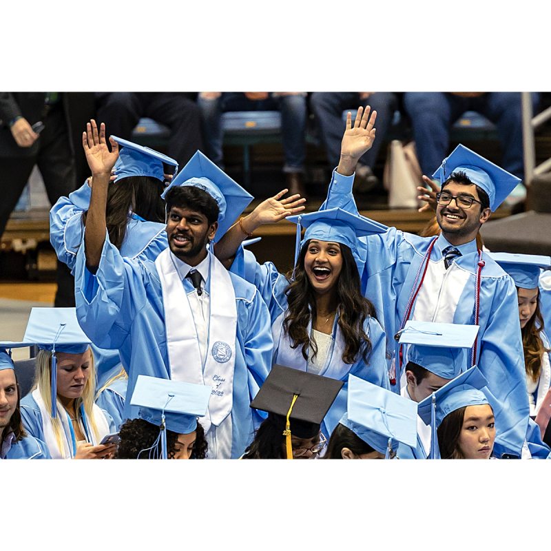 Graduates waving at a commencement ceremony.