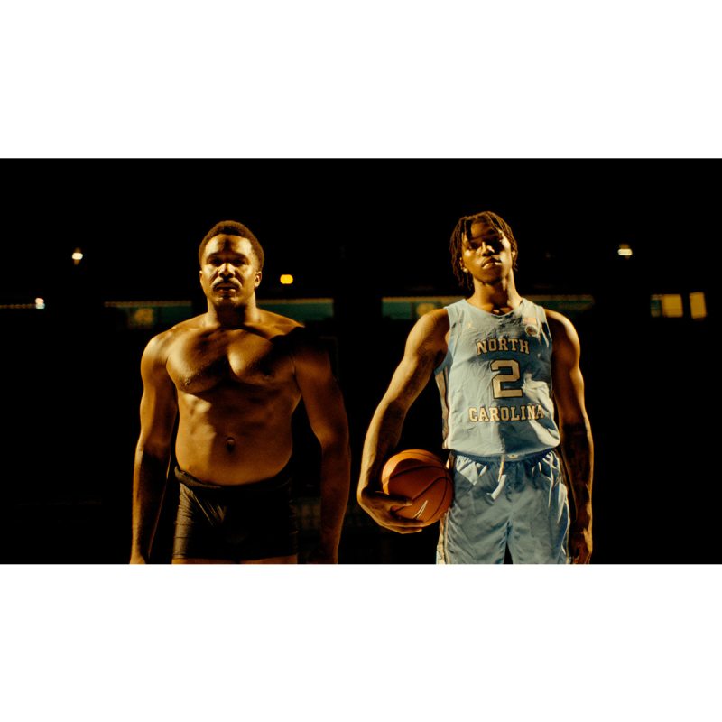 A shirtless male dancer and a basketball plyer holding a basketball posing for a photo.