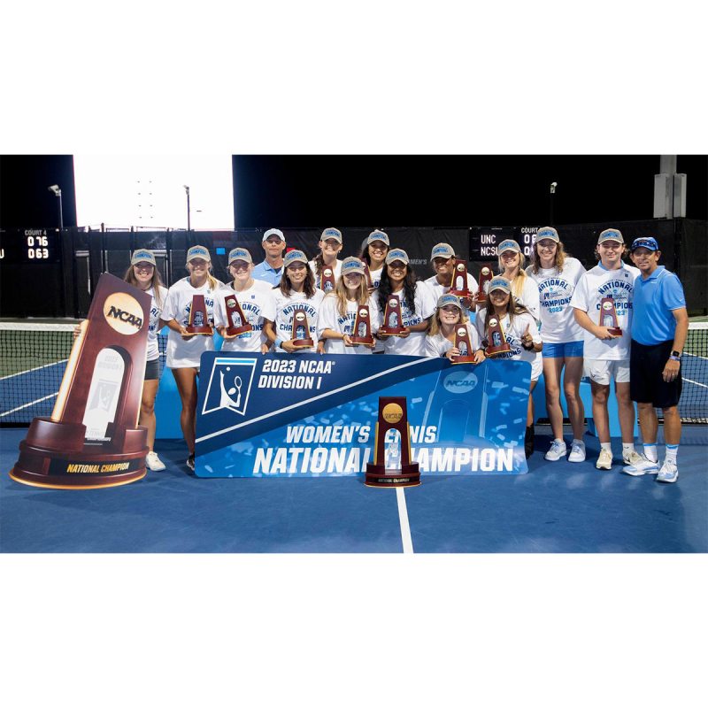 The Carolina women's tennis team posing for a team photo in front of a 