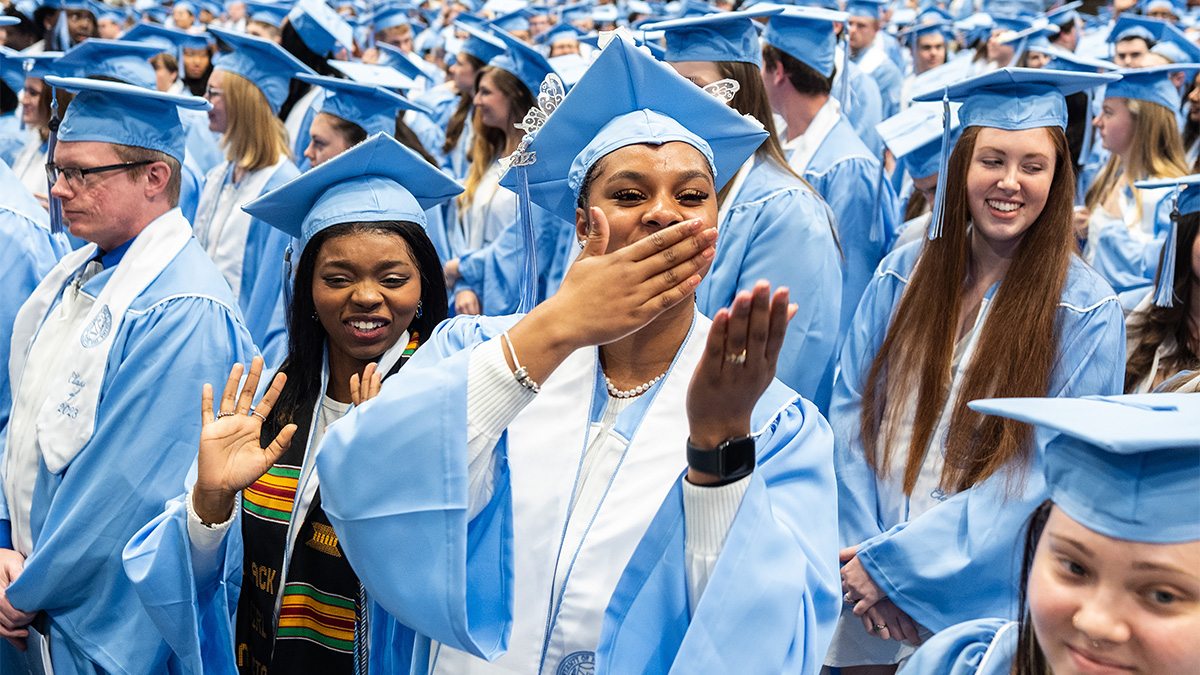 A graduate blowing a kiss with her hand at Winter Commencement.