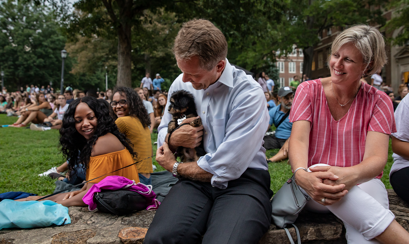 Kevin M. Guskiewicz holding a small dog at the Sunset Serenade event on Polk Place on the campus of UNC-Chapel Hill.