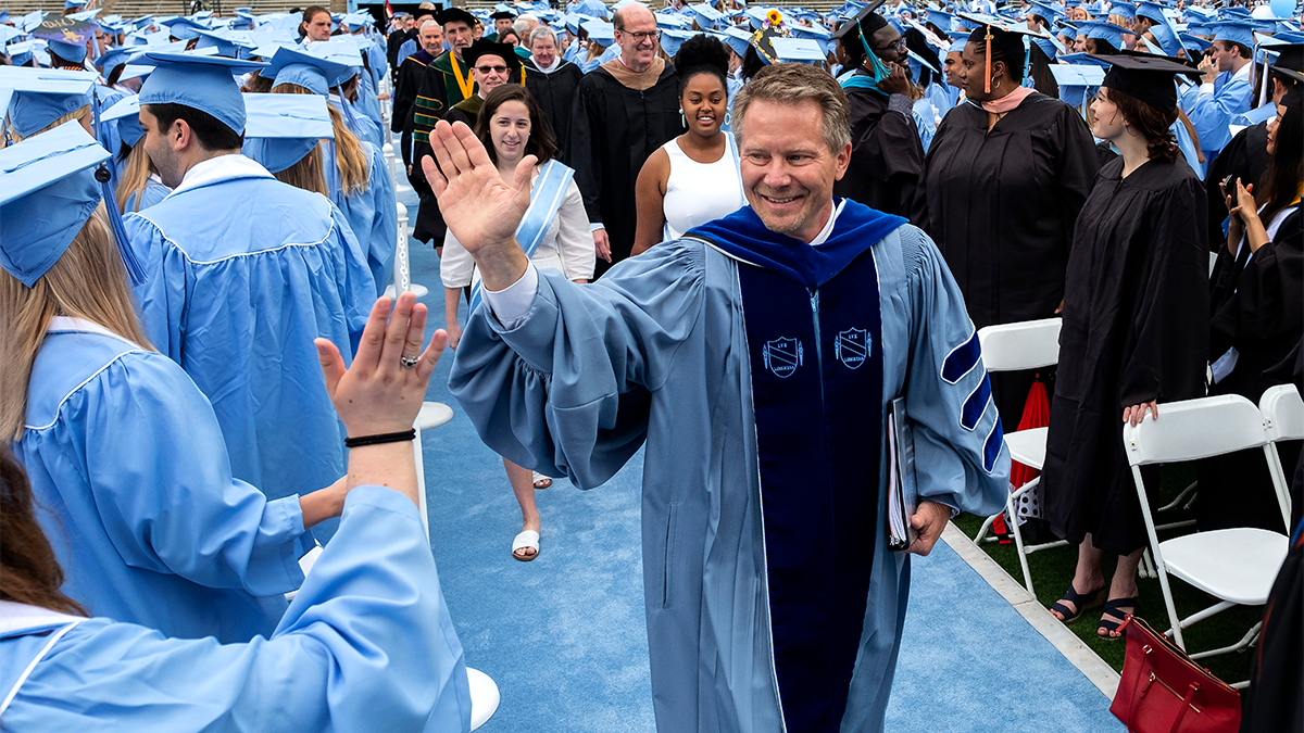 Kevin M. Guskiewicz high-fiving graduates at Spring Commencement.