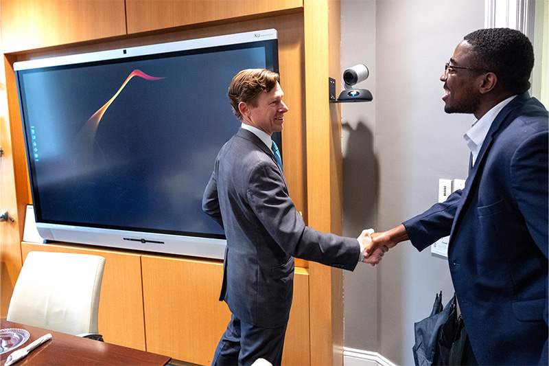 Interim Chancellor Lee H. Roberts shaking hands with Student Body President Christopher Everett inside of a meeting room.