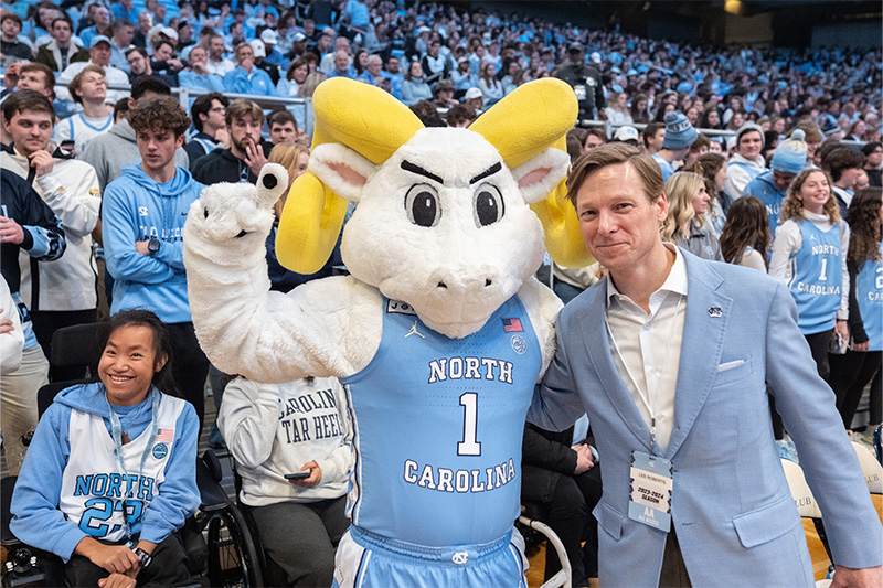 UNC-Chapel Hill's ram mascot, Rameses, posing for a photo with Interim Chancellor Lee H. Roberts at a men's basketball game inside of the Dean E. Smith Center.