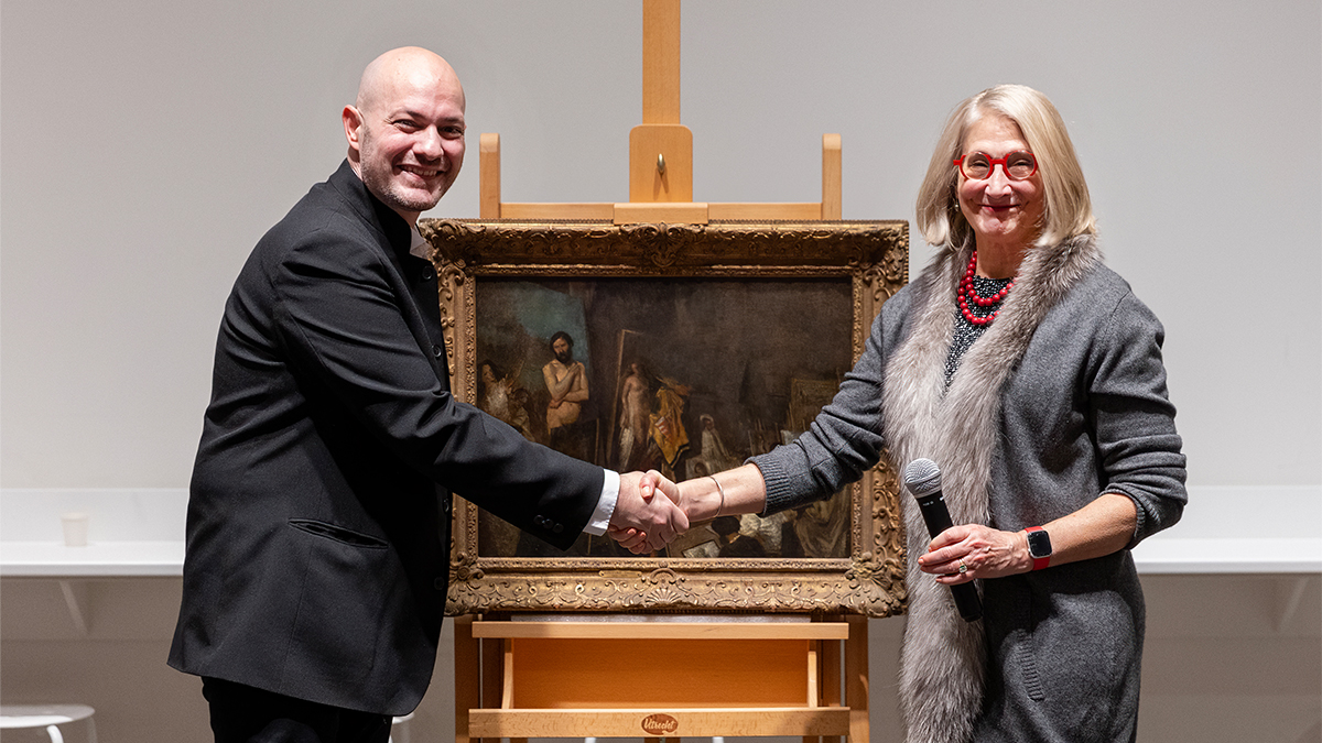 Raphaël Falk and Katie Ziglar shake hands in front of framed artwork; 
