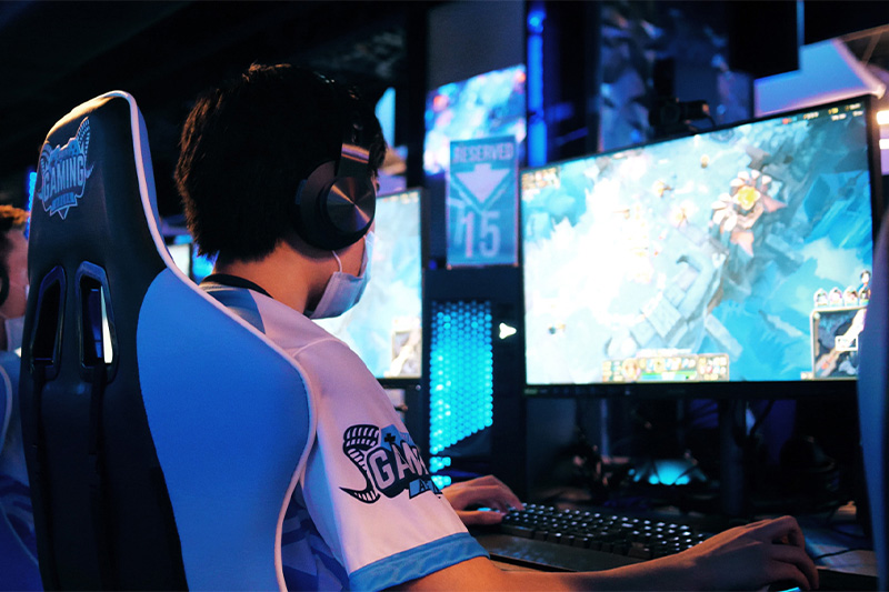 A student sitting in front of a monitor and keyboard in an on-campus e-sports arena at UNC-Chapel Hill