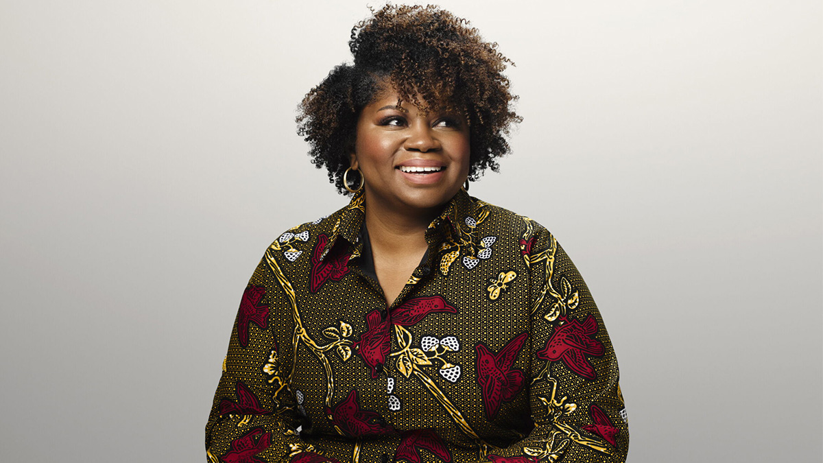 Stephanie Headley smiling, wearing a patterned shirt in front of a grey backdrop.