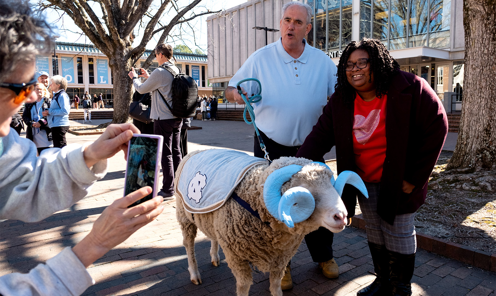A woman posing with a live ram mascot, Rameses, at the Pit on the campus of UNC-Chapel Hill.