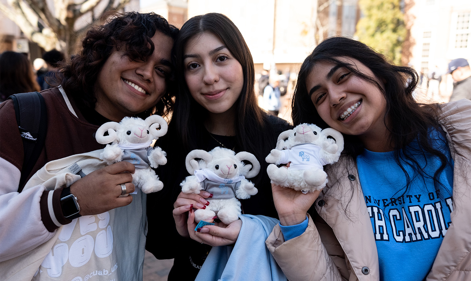 Three students holding up their stuffed animal Rameses.