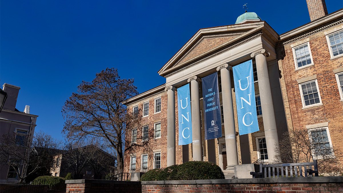 Exterior of South Building on the campus of UNC-Chapel Hill with Carolina Blue and Navy Blue banners.