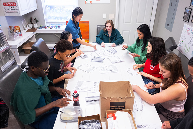 UNC-Chapel Hill students sitting at a table and packaging opioid overdose rescue kits at Queen City Harm Reduction in Charlotte
