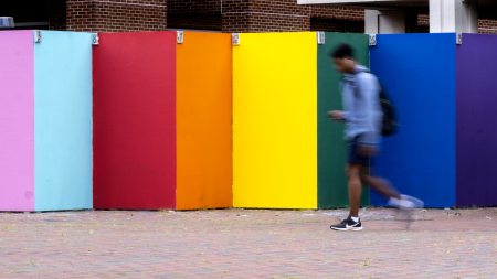 Person walking by rainbow-colored wall