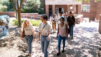 A group of graduate students walking on a brick pathway on the campus of UNC-Chapel Hill.
