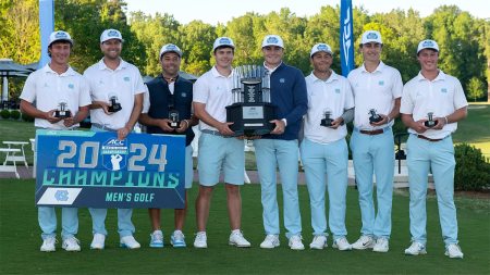 Members of the Carolina men's golf team posing for a group photo after winning the ACC championship while holding a trophy and a banner that reads 