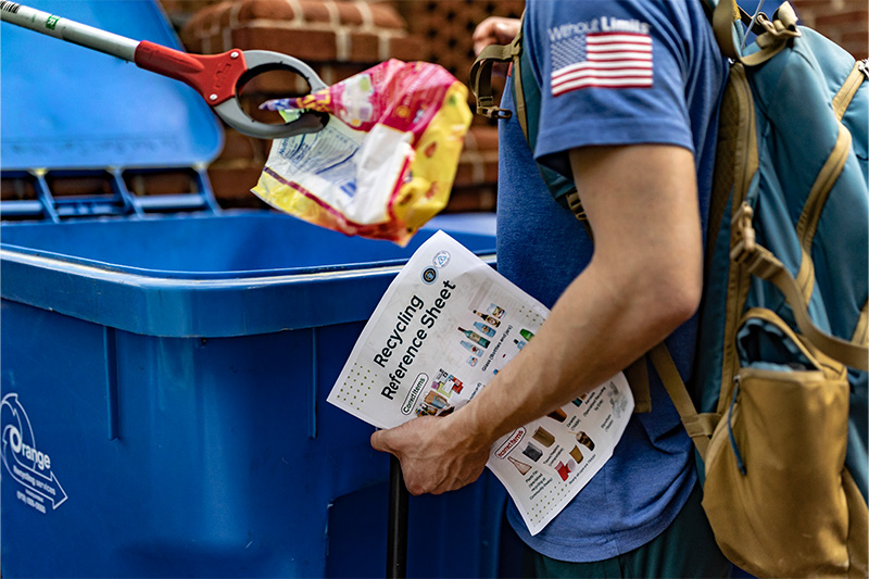 A student inspecting items inside a recycling bin