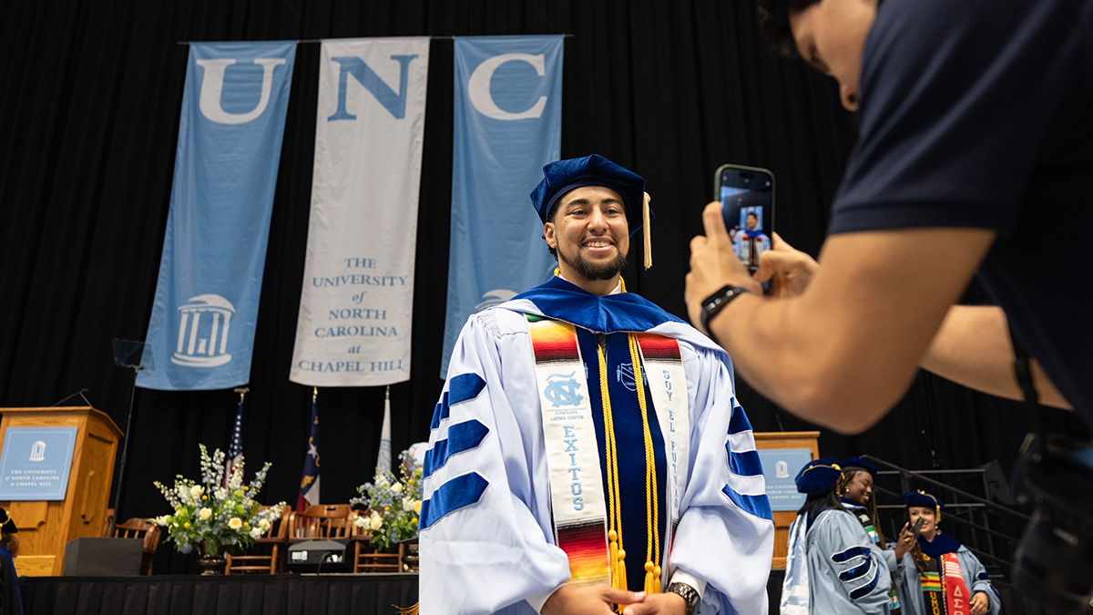 Graduate student poses for photo in front of UNC banner